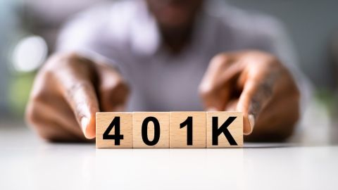Hombre señala cuadros de madera con las letras del plan 401(k).