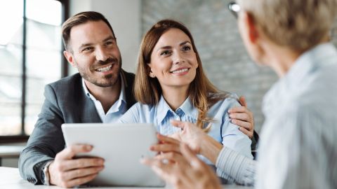 Una joven pareja feliz hablando un asesor financiero.