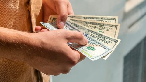 Un hombre tiene billetes de cien dólares en sus manos tras pedir un cash advance.
