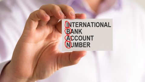 Primer plano de un hombre de negocios sosteniendo una tarjeta con el mensaje NÚMERO DE CUENTA BANCARIA INTERNACIONAL IBAN,