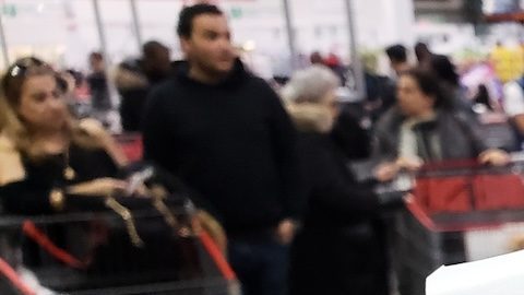 Una mano que sostiene un recibo y una tarjeta de membresía de Costco en el almacén de Costco.