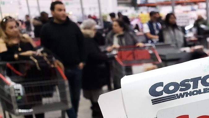 Una mano que sostiene un recibo y una tarjeta de membresía de Costco en el almacén de Costco.