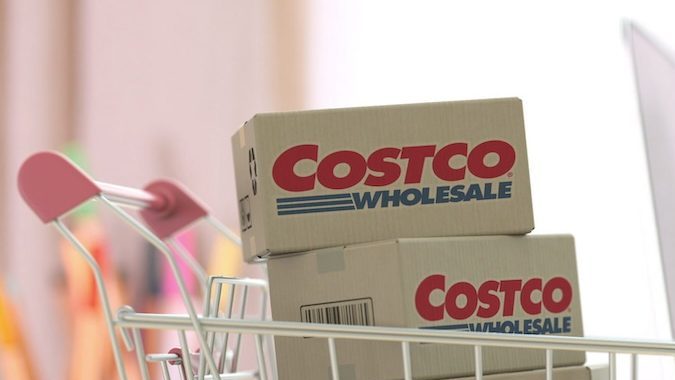 Cajas con el logo de COSTCO WHOLESALE en el carrito de compras cerca de la computadora.