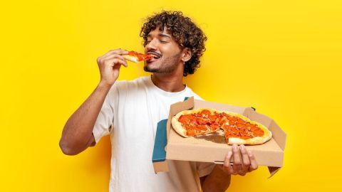 Joven disfrutando de una pizza gratis de la nueva promoción de Domino’s y Uber Eats.