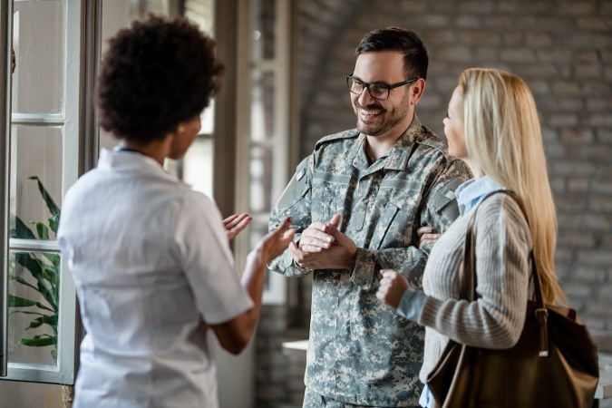 Feliz soldado del ejército y su esposa comunicándose con una trabajadora de la salud.