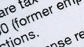 Bolígrafo, libreta y dólares sobre el formulario de impuestos W-2.