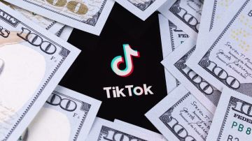 Aplicación móvil con el logotipo de TikTok en la pantalla del teléfono inteligente iPhone con dólares en primer plano.
