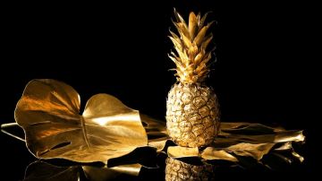 Piña dorada frente a un fondo negro.