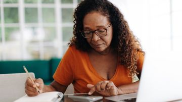 Mujer mayor haciendo cálculos sobre su anualidad de jubilación.