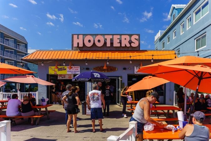 Fachada de un restaurante Hooters con clientes afuera en Ocean City, MD.