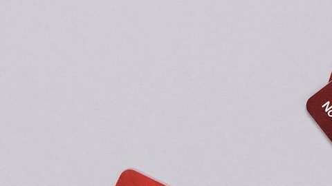 Mano sostiene las tarjetas de regalo de color rojo al por mayor de Costco sobre fondo gris.