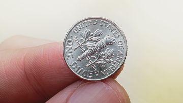 Moneda de 10 centavos de dólar entre los dedos.