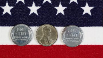 Vista de cerca de las piezas de un centavo de los Estados Unidos, fechas originales de la Segunda Guerra Mundial, colocadas en la bandera estadounidense.