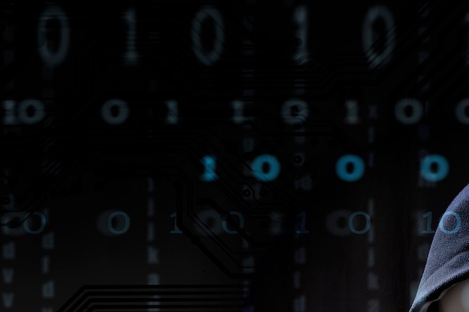 Hacker enmascarado está usando una computadora.