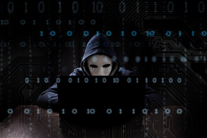 Hacker enmascarado está usando una computadora.