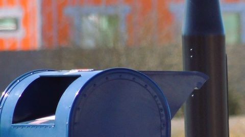 Un trabajador postal de USPS recoge el correo saliente en un buzón de entrega.