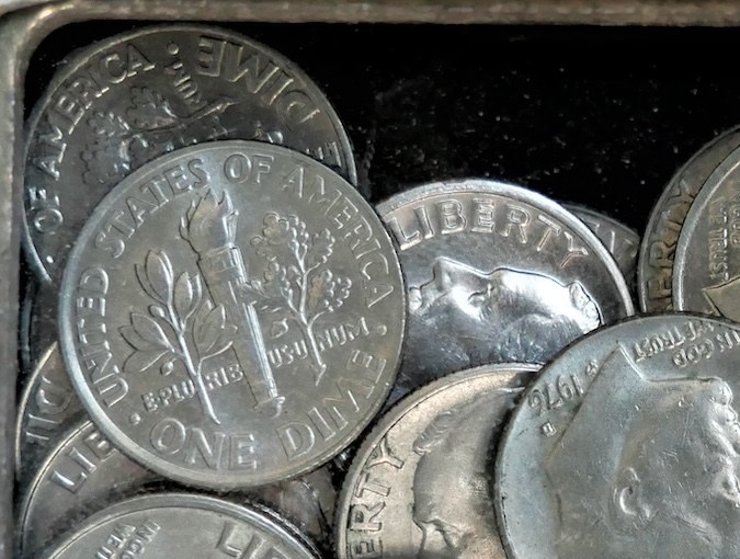 Caja con muchas monedas de 10 centavos de dólar.