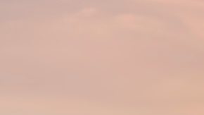 Joven nómada digital sentado en un muelle de madera en el mar trabajando en Internet remotamente al atardecer.