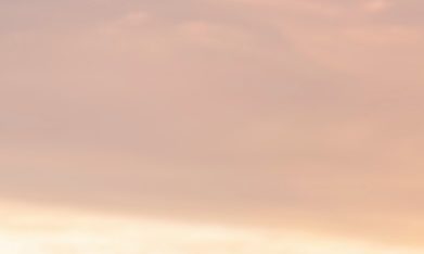 Joven nómada digital sentado en un muelle de madera en el mar trabajando en Internet remotamente al atardecer.
