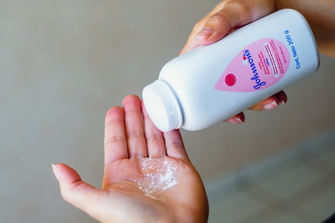 Una persona usa talco para bebés Johnson & Johnson en sus manos.