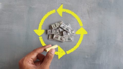 Mano dibuja fechas circulares alrededor de dinero, representando el flujo de dinero o money flow.