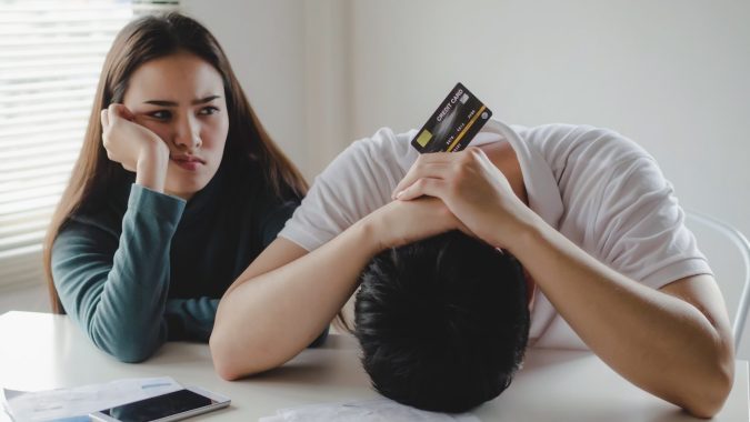 Pareja joven estresada con tarjeta de crédito y preocupada por las facturas.