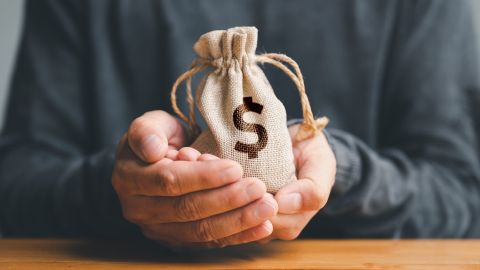 Manos de hombre sostienen una bolsa de dinero que representa un préstamo de emergencia.