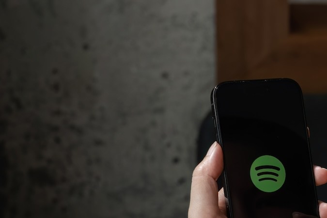 Persona que sostiene un nuevo Apple iPhone 14 con el logotipo de Spotify en la pantalla.