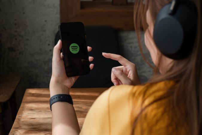 Persona que sostiene un nuevo Apple iPhone 14 con el logotipo de Spotify en la pantalla.