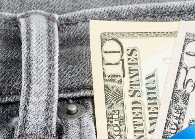 Billete de dólar estadounidense y tarjeta de crédito en el bolsillo del jean gris.