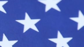 Sitio web oficial del IRS en la pantalla del iPhone 12 pro con formularios de impuestos en papel 1040 y w-2 en la bandera de los Estados Unidos.