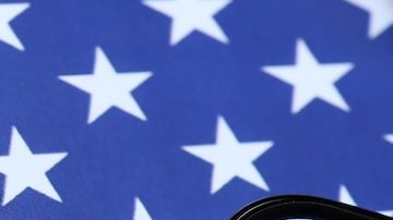 Sitio web oficial del IRS en la pantalla del iPhone 12 pro con formularios de impuestos en papel 1040 y w-2 en la bandera de los Estados Unidos.