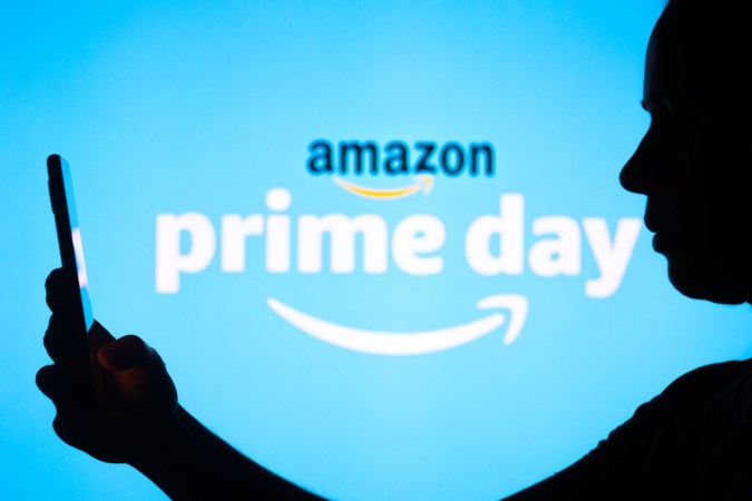 El logotipo de Amazon Prime Day se ve en el fondo de una silueta de mujer sosteniendo un teléfono móvil.