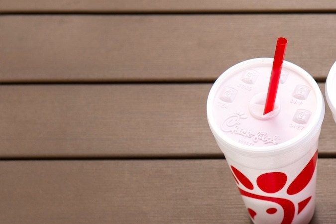 Chick fil una bolsa junto a vasos de cola, pollo con tiras y hamburguesa picante.