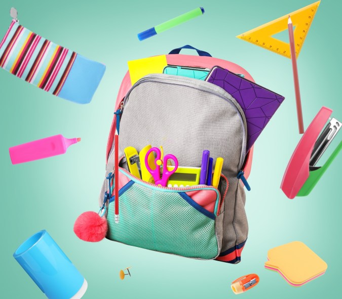 Mochila rodeada de papelería de la escuela de vuelo sobre fondo verde pálido.