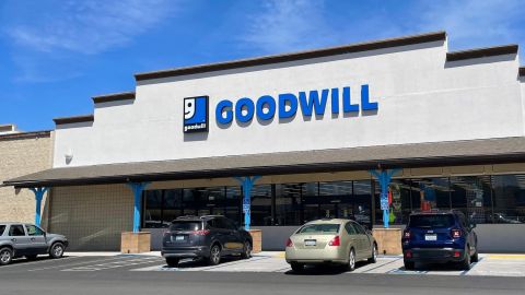 Fachada de una tienda Goodwill desde el estacionamiento en un día soleado bajo un cielo azul.