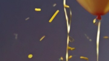 Mujer sonriente con una dona rosa en la mano.