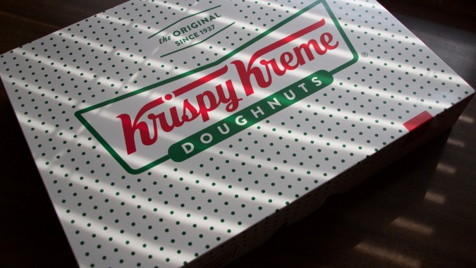 logotipo de Krispy Kreme en una caja de donuts bajo la sombra de la luz solar natural.