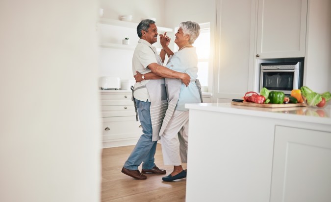 Una pareja feliz,de edad avanzada baila juntos en la cocina y siente amor, emoción y unión en casa.