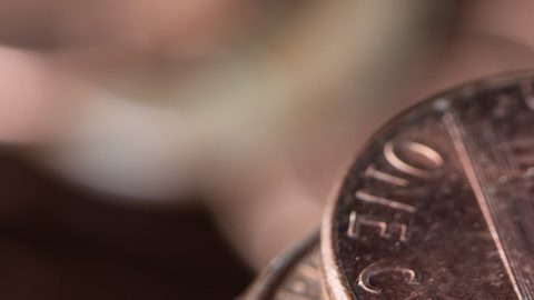 Foto en primer plano de un montón de monedas de 1 centavo de dólar con más monedas al fondo.