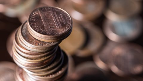 Foto en primer plano de un montón de monedas de 1 centavo de dólar con más monedas al fondo.