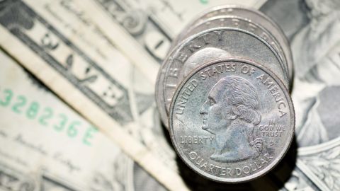 Columna de monedas de 25 centavos de dólar sobre billetes de EE.UU.