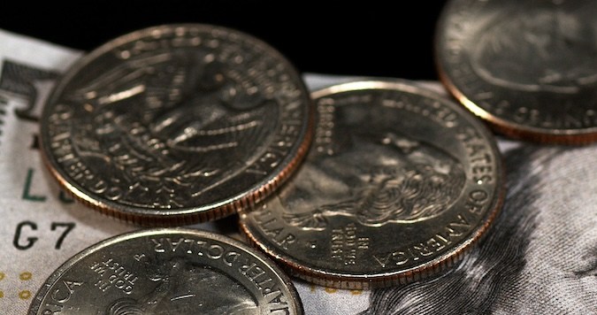 Monedas de un cuarto de dólar cayendo, rodando y deslizándose sobre fondo negro.