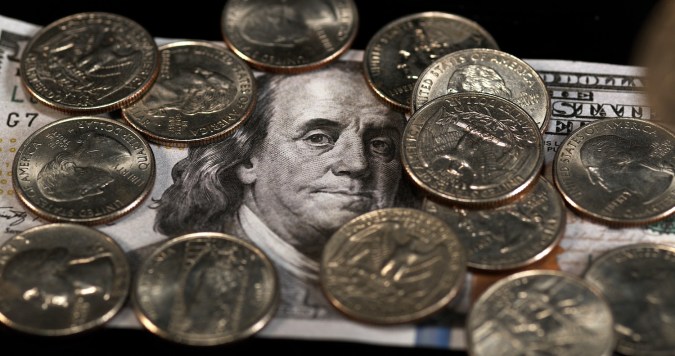 Monedas de un cuarto de dólar cayendo, rodando y deslizándose sobre fondo negro.