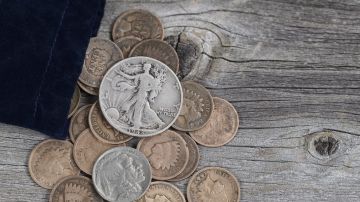 Vista de cerca de una bolsa de monedas antiguas de los Estados Unidos derramándose sobre madera rústica