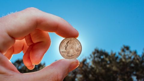 Moneda de 25 centavos de dólar sostenida contra el sol.