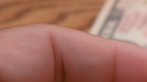 La mano de un hombre sostiene una moneda de 25 centavos de dólar.