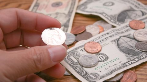 La mano de un hombre sostiene una moneda de 25 centavos de dólar.