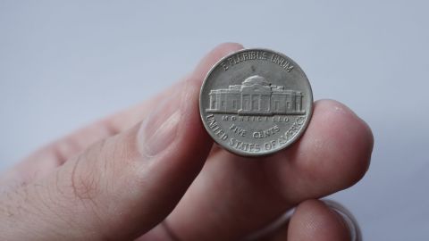 Moneda «Jefferson Nickel» (5 centavos) entre los dedos.