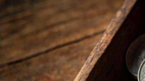 Vista cenital de una caja de madera con monedas de plata dentro.